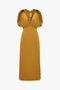 A Victoria Beckham V-Neck Ruffle Midi Dress In Harvest Gold featuring short shoulder frills, an empire waistline, and a deep V-neckline, displayed on a plain white background.