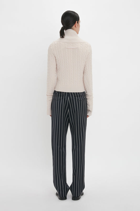 A person with dark hair is standing with their back to the camera, wearing a light pink turtleneck sweater and **Victoria Beckham Tapered Leg Trouser In Midnight-White**.
