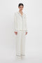 A person is standing against a white background wearing the VB Monogram Pyjama Sleep Set In Ivory by Victoria Beckham.