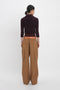 Person wearing a dark Victoria Beckham Double Layer Top In Deep Mahogany and tan utility pants with large pockets, standing and facing away from the camera against a white background.