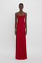 Person standing against a plain white background, wearing a floor-length, 1990s-inspired Low Back Cami Floor-Length Dress In Poppy Red by Victoria Beckham with thin straps and a flattering fit.