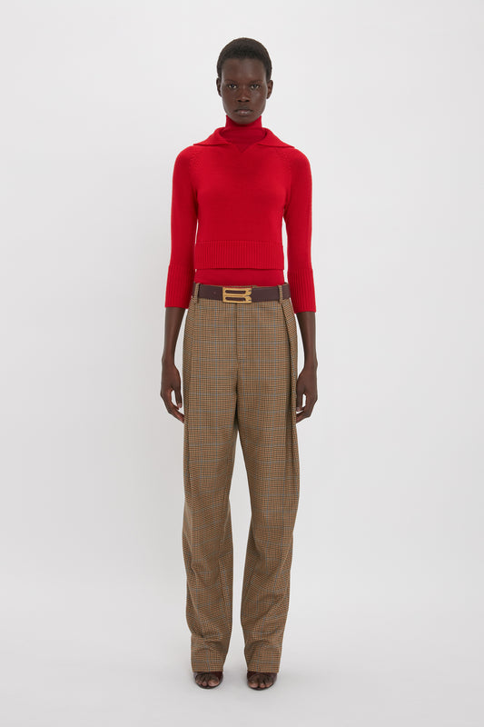 Person standing against a white background wearing a Victoria Beckham Double Layer Top In Deep Red, brown checkered pants, and a brown belt with a gold buckle.