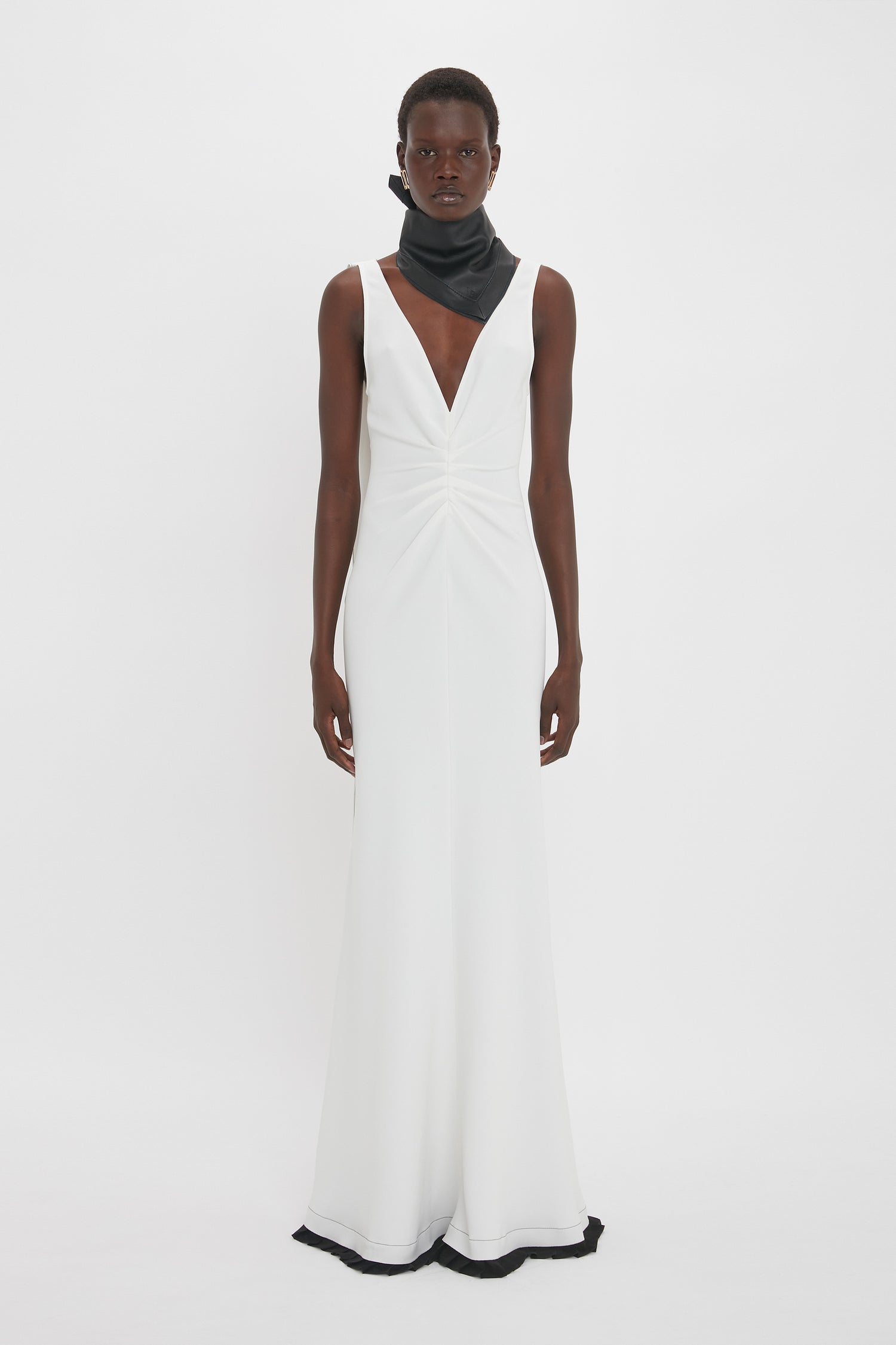 Person wearing an Exclusive V-Neck Gathered Waist Floor-Length Gown In Ivory by Victoria Beckham with a black scarf around the neck, showcasing an hourglass silhouette, standing against a plain white background.
