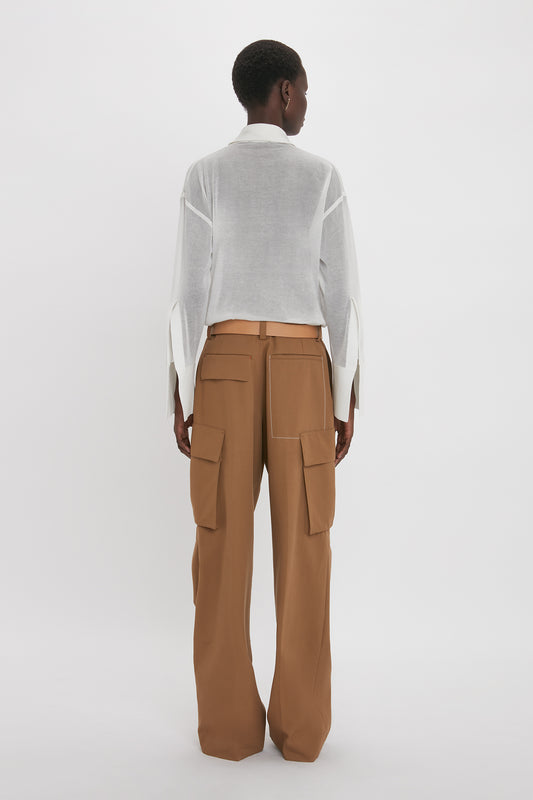 Person standing against a plain background, wearing a Victoria Beckham Pocket Detail Shirt In White and brown cargo pants with multiple pockets.
