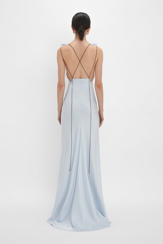 A person in an Exclusive Gathered Shoulder Cami Floor-Length Gown In Ice Blue by Victoria Beckham stands facing away against a plain white background.