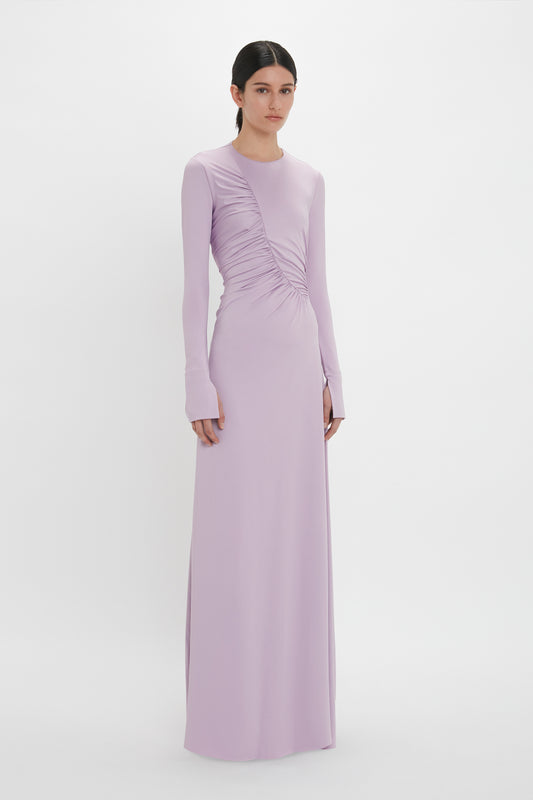 Person standing against a white background, wearing an understated glamour Ruched Detail Floor-Length Gown In Petunia from Victoria Beckham made from stretch jersey with ruched detailing on the bodice.