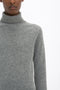 Person wearing a Victoria Beckham Polo Neck Jumper In Grey Melange, photographed from the chest to head against a white background.