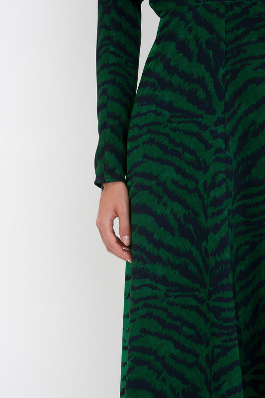 Close-up of a person in a Dolman Midi Dress In Green-Navy Tiger Print by Victoria Beckham, focusing on the fabric and the person's hand by their side.