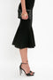 A person is wearing a black VB Body Scallop Trim Flared Skirt In Black by Victoria Beckham, black high-heeled shoes, and holding a black clutch bag with a gold detail.