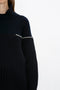 Person wearing a dark-colored, high-neck Victoria Beckham Collar Detail Jumper In Navy with a ribbed texture and a contrasting white stripe across the upper chest and sleeves.