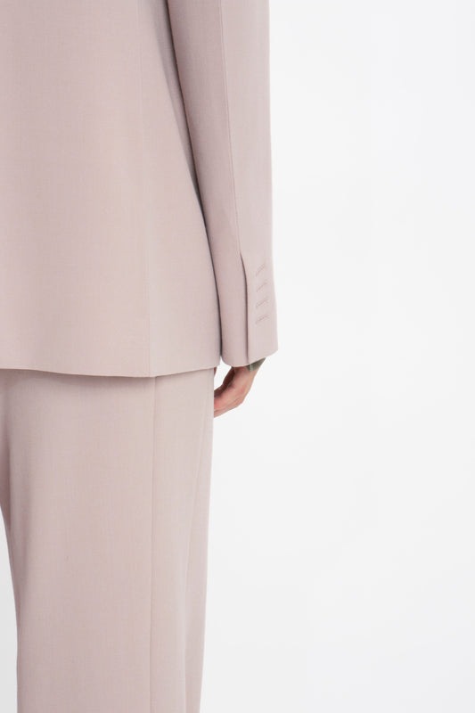 Close-up view of the back of a person wearing a light beige, classic tailored Victoria Beckham Double Panel Front Jacket In Rose Quartz. The image focuses on the suit's sleeve and side seam, highlighting the meticulous craftsmanship.