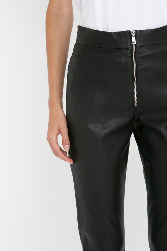 A person wearing Victoria Beckham Slim Leather Trouser in Black with a front zipper stands against a plain white background.