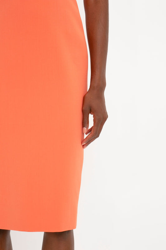 Close-up of a person in an orange Victoria Beckham Fitted T-Shirt Dress In Papaya, showing a hand resting on their hip.