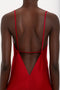 A person is wearing a Victoria Beckham Low Back Cami Floor-Length Dress In Poppy Red, featuring a flattering fit with thin straps and an elegant backless design.