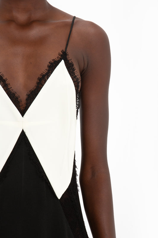 Close-up of a person wearing the Victoria Beckham V-Neck Lace Insert Cami Dress In Ivory, featuring a geometric design on the front.