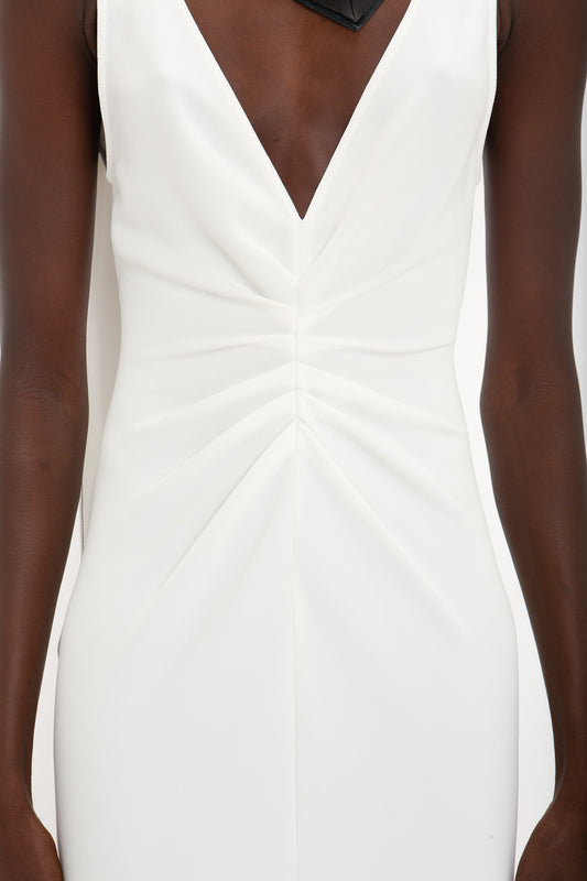 Close-up of a person wearing an **Exclusive V-Neck Gathered Waist Floor-Length Gown In Ivory by Victoria Beckham**, featuring a black necklace that complements the hourglass silhouette.
