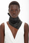 A person wearing a white V-neck sleeveless top, a supple **Victoria Beckham Leather Scarf In Black**, and gold rectangular earrings stands against a white background.