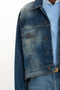 A person wearing a Victoria Beckham Cropped Denim Jacket In Heavy Vintage Indigo Wash over a blue and white striped shirt. Only the right side of the torso is visible.