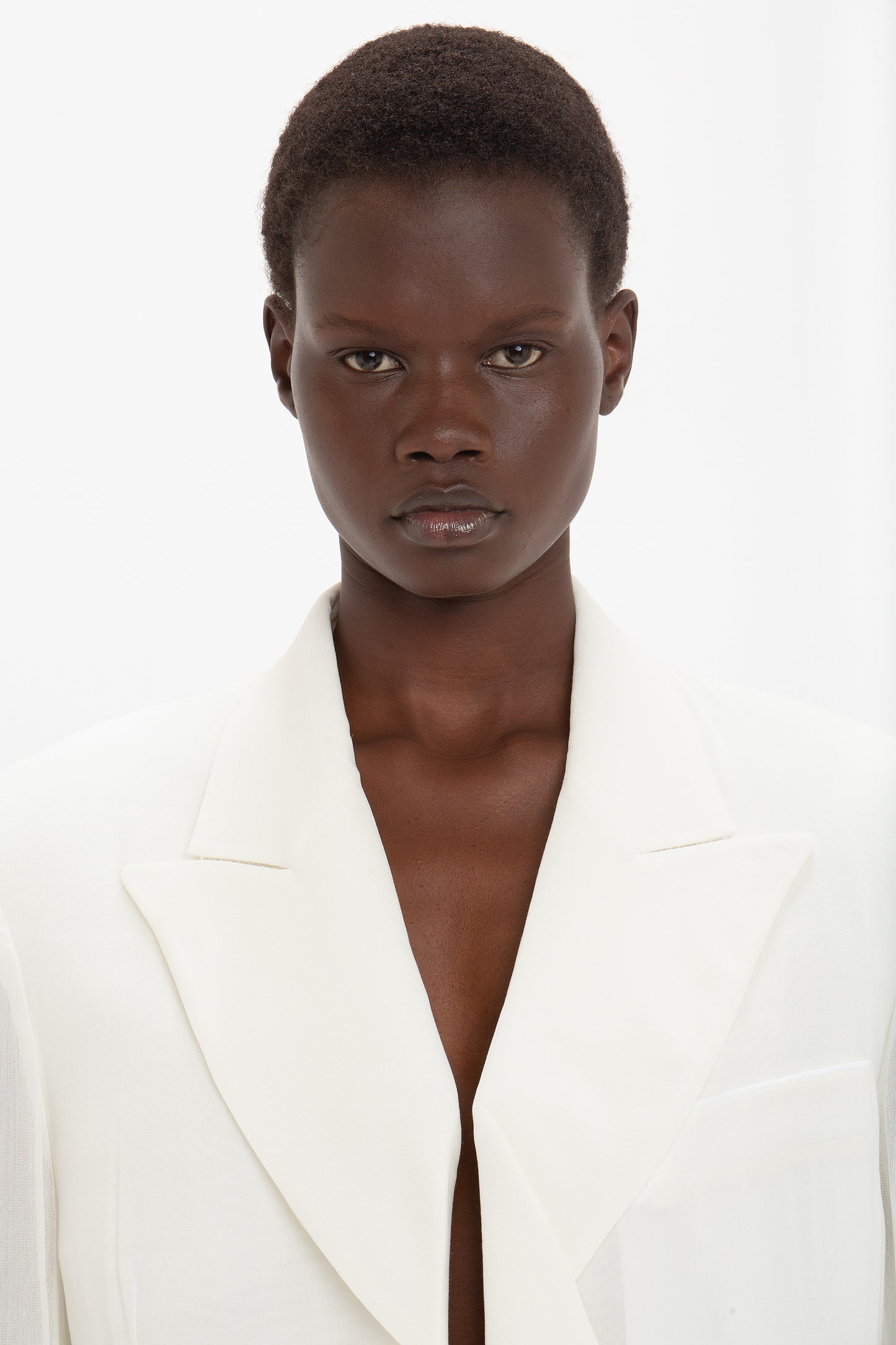 Person with short hair in a featherweight wool, Victoria Beckham Fold Detail Tailored Jacket In White looking directly at the camera against a plain background, exuding modern flair.
