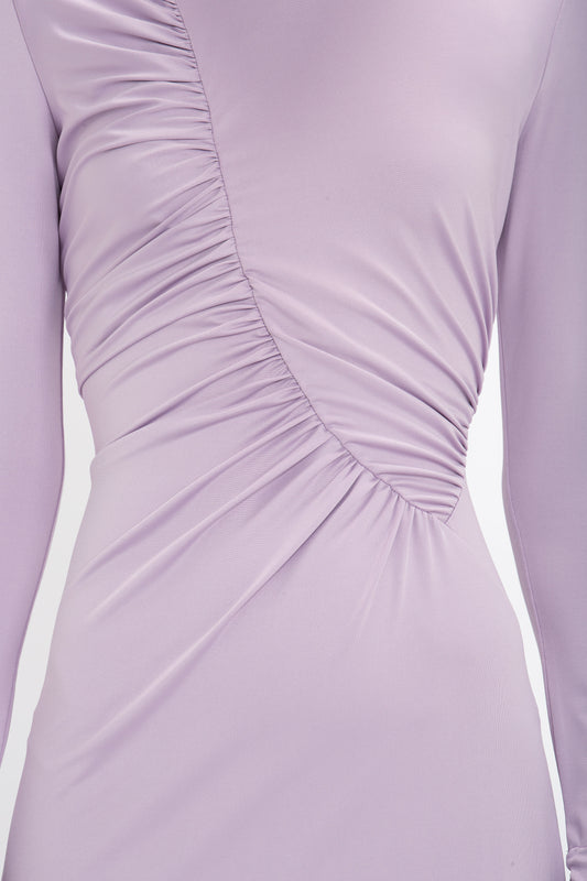 Close-up of a lavender-colored, long-sleeve Ruched Detail Floor-Length Gown In Petunia by Victoria Beckham made from stretch jersey with ruched detailing diagonally across the fabric.