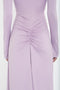 A close-up of the back of a person wearing a long-sleeved, fitted Victoria Beckham Ruched Detail Floor-Length Gown In Petunia in lavender stretch jersey with ruched detail at the waist.