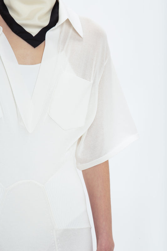 Close-up of a person wearing the Victoria Beckham Panelled Knit Dress In White with pockets and a black and white neck scarf, exuding relaxed glamour. Only the torso and neck are visible against a plain white background, creating an effortlessly chic look.