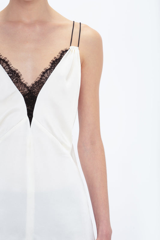 A person wearing the Victoria Beckham Lace Detail Cami Top In Harvest Ivory, reminiscent of a 1990s cami top, featuring thin shoulder straps and crepe back satin fabric, against a plain white background.