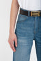 A person wearing light blue, distressed **Julia Jean In Broken Vintage Wash** jeans by **Victoria Beckham** with a black belt featuring a gold buckle, and a white t-shirt. The image shows the lower half of the torso and part of the hand at the side.