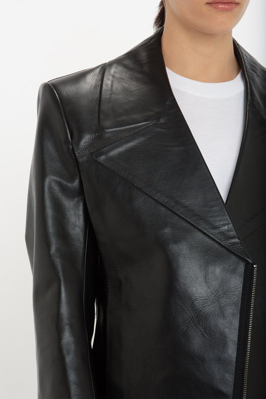 A person wearing the Victoria Beckham Tailored Leather Biker Jacket In Black made of calf leather over a white shirt, with a visible zipper along the front.
