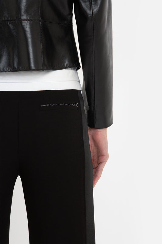 A person in a modern classic, Victoria Beckham Tailored Leather Biker Jacket In Black and black pants is standing with their back facing the camera. Only the upper waist and arms are visible.