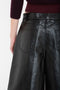 A person wearing black Victoria Beckham Leather Bermuda Short In Black shown from the back. The shorts feature visible back pockets and seam details. The person is also wearing a maroon sweater.