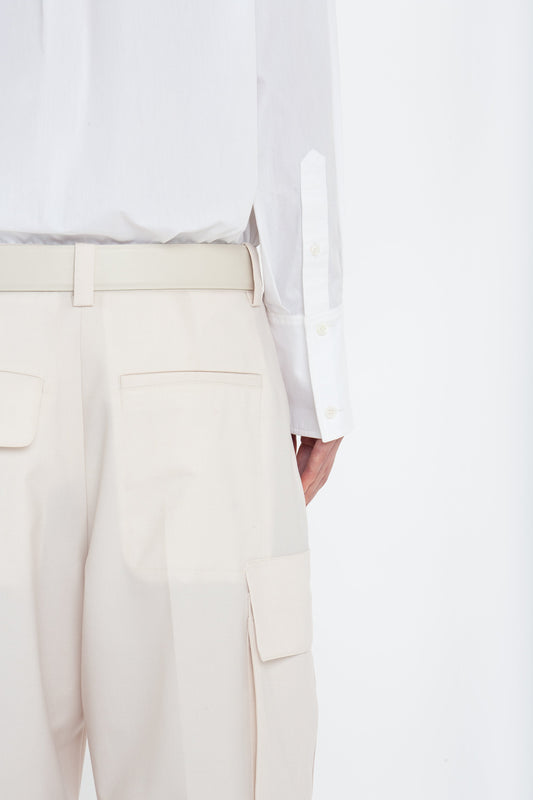A person wearing Victoria Beckham's Relaxed Cargo Trouser In Bone with pocket details and a white shirt, photographed from the back.