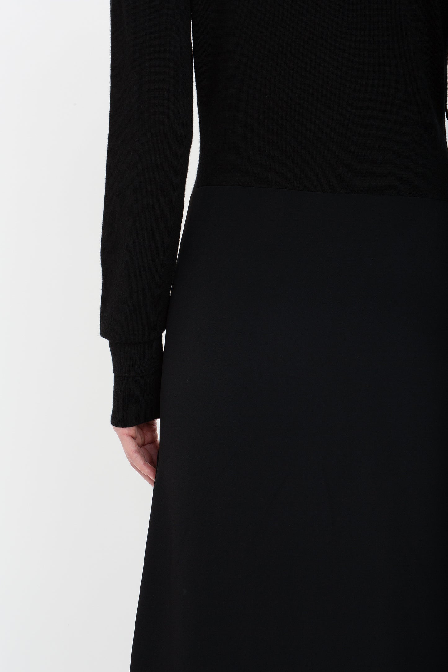 Close-up of a person wearing a Henley Shirt Dress In Black by Victoria Beckham, showing their back and left arm, highlighting the intricate design of an asymmetric waist seam.