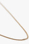 Close-up image of a thin, gold-plated brass chain necklace, the Exclusive Long Fine Chain In Gold by Victoria Beckham, against a white background.