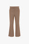 Wide Cropped Flare Trouser In Tobacco by Victoria Beckham, reminiscent of 1970s-inspired trousers. The pants have a waistband and no visible pockets or embellishments, offering a contemporary kick hem. They are set against a solid white background.