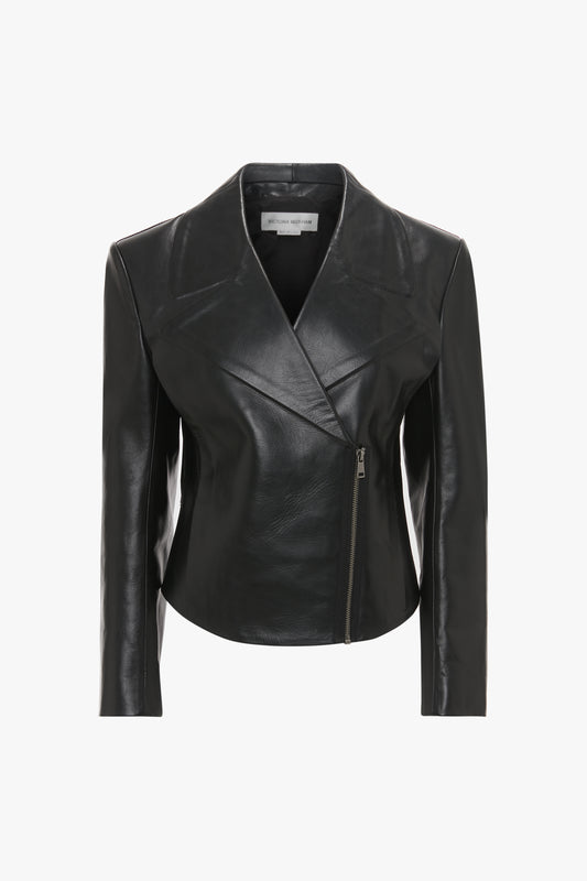 A black calf leather jacket with an asymmetrical front zipper and a minimalist collar, exuding a modern classic vibe, displayed on a white background is the Tailored Leather Biker Jacket In Black by Victoria Beckham.