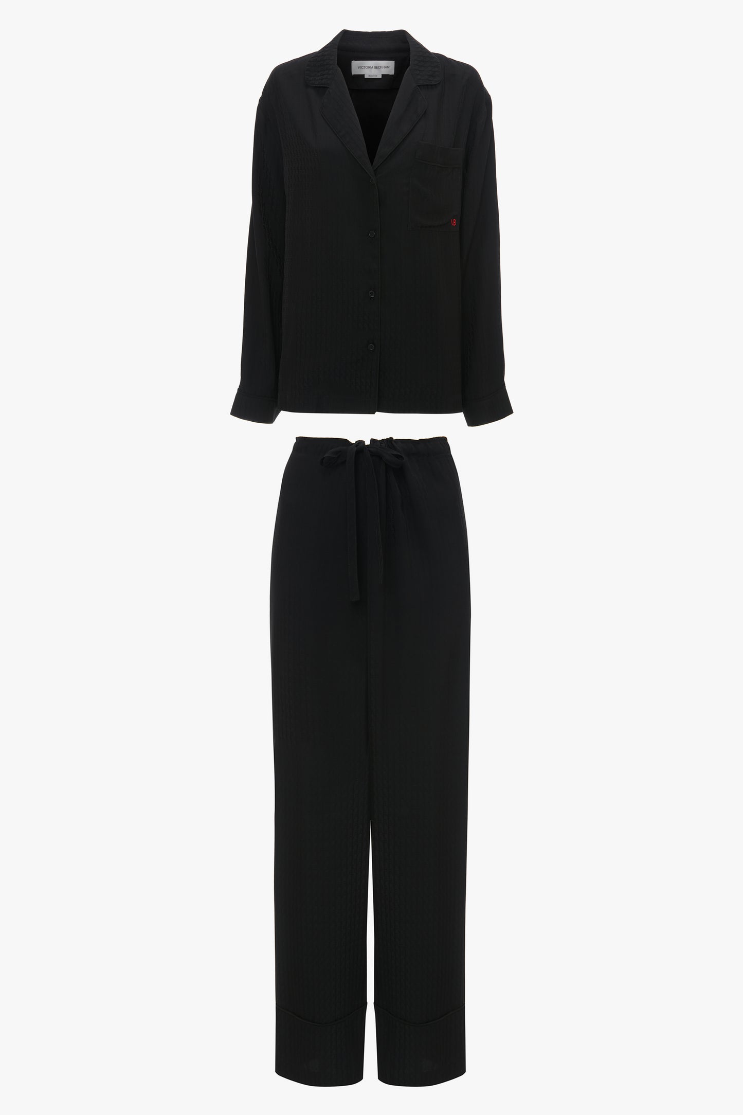 A black two-piece outfit consisting of a long-sleeve button-up shirt and wide-leg pants with a drawstring waist, reminiscent of luxurious loungewear, displayed on a white background is the VB Monogram Pyjama Sleep Set In Black by Victoria Beckham.