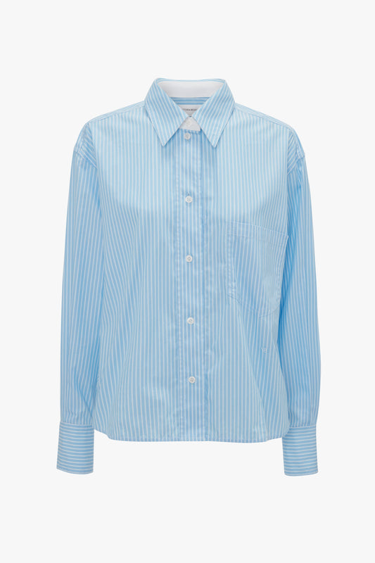 A Victoria Beckham Cropped Long Sleeve Shirt In Marina-White with white vertical pinstripes, long sleeves, a front pocket, and a classic collar, reminiscent of traditional men's shirting.