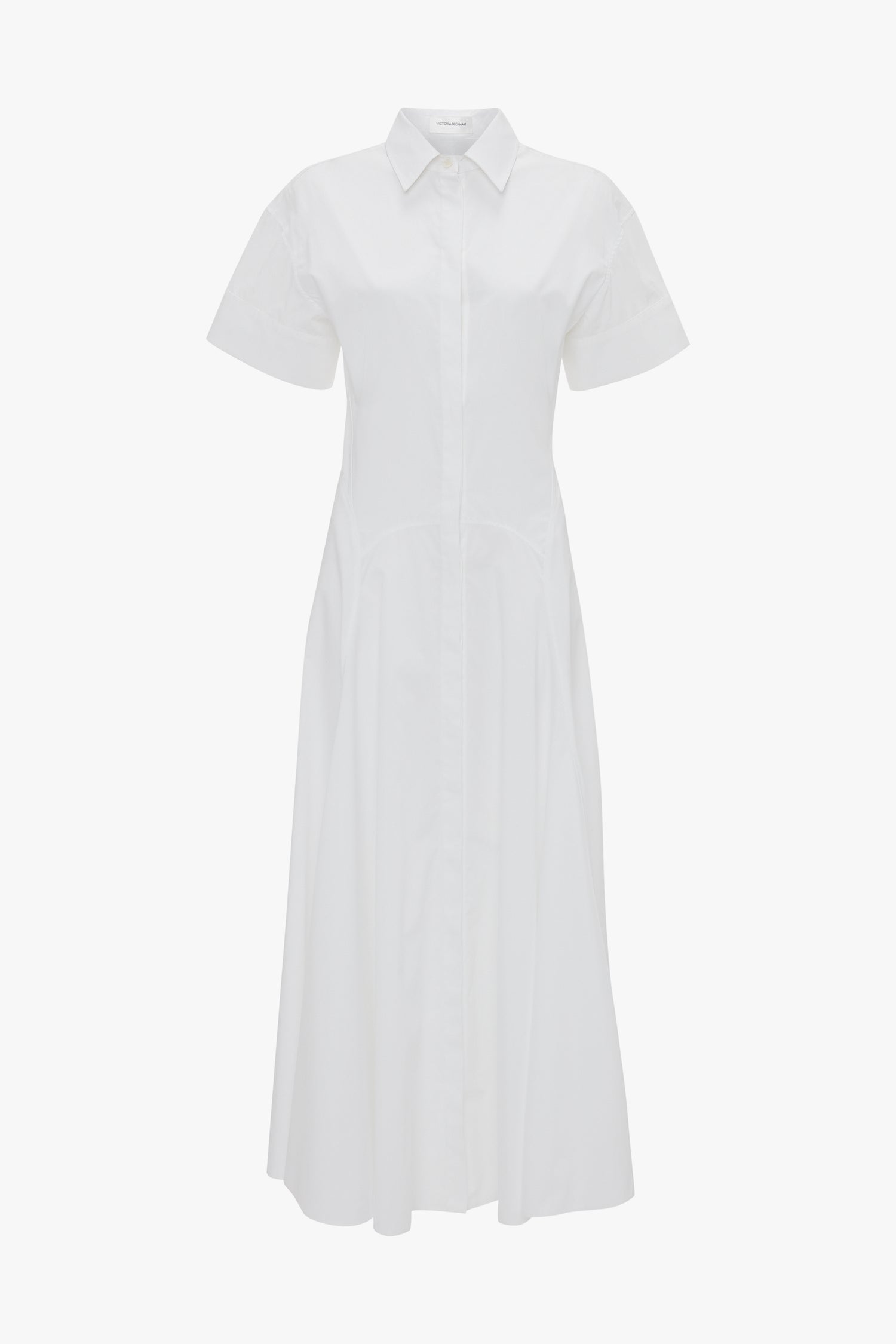 Victoria Beckham's Panelled Shirt Dress In White is a white short-sleeve, button-down dress crafted from organic cotton poplin with a collared neckline, gold button cuffs, and an ankle-length hem.