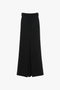 A figure-flattering, black, high-waisted, wide-leg skirt made from pure wool features a front slit and belt loops on the waistband. Introducing the Floor-Length Box Pleat Skirt In Black by Victoria Beckham.