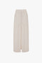 A long, off-white Deconstructed Floor-Length Skirt In Bone by Victoria Beckham with vertical stitching details, front slit, and two side pockets exudes relaxed refinement against a plain white background.