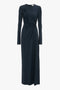 A long-sleeved, dark navy blue Ruched Detail Floor-Length Gown In Midnight by Victoria Beckham with an asymmetrical design on the front and a rounded neckline, exuding understated glamour.