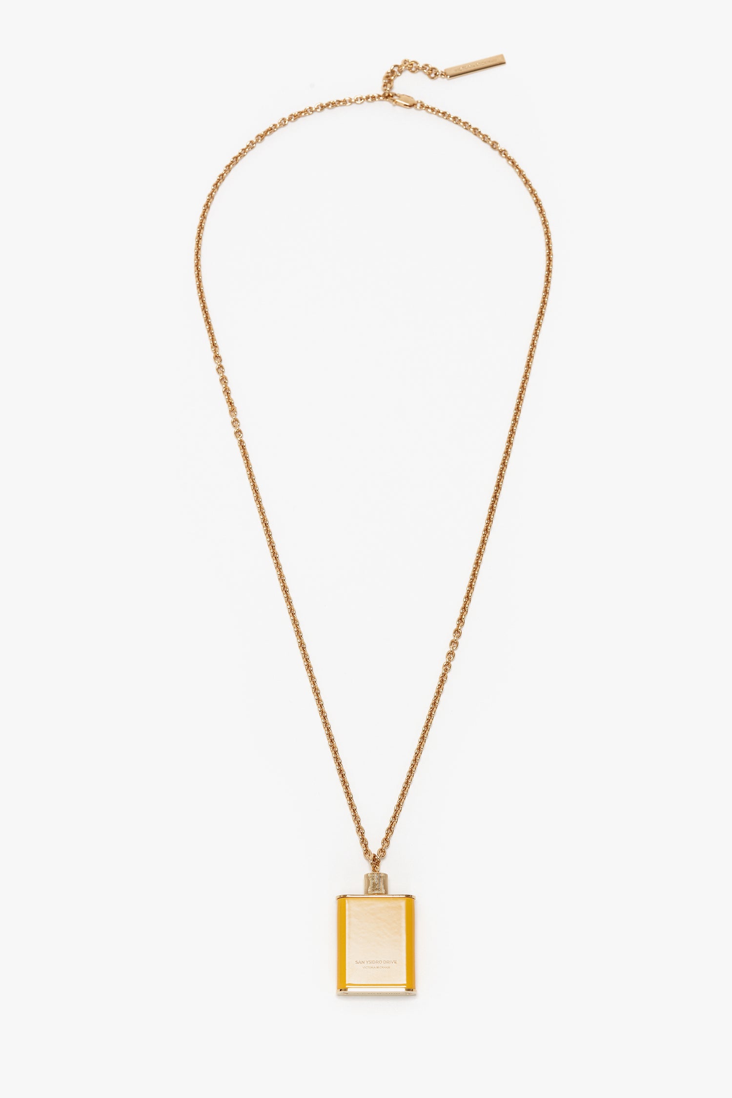 A gold-plated pendant necklace featuring a rectangular charm with a small top ring, hanging from a fine chain with an adjustable clasp. The charm is crafted in gold brushed brass, adding an extra touch of elegance to this exquisite piece: the Perfume Bottle Necklace In San Ysidro Drive by Victoria Beckham.