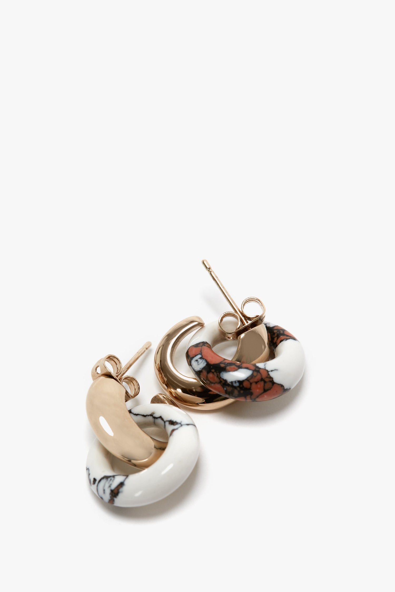 A pair of Exclusive Resin Pendant Earrings In Light Gold-White with circular designs; one features white and brown marbling, and the other showcases solid gold and beige segments, both expertly crafted in Italy with a gold metal post and antiallergic stainless-steel closure by Victoria Beckham.