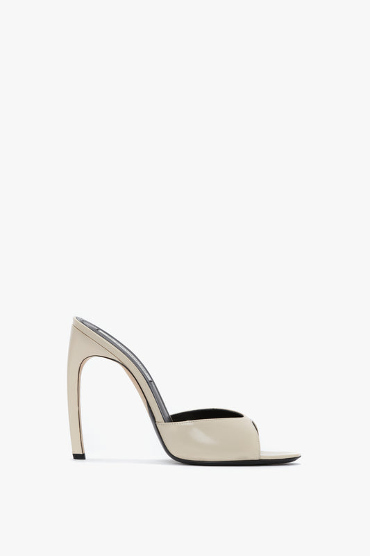 A side view of the Classic Mule In Macadamia calf Leather by Victoria Beckham showcases an open toe and a unique curved heel design.