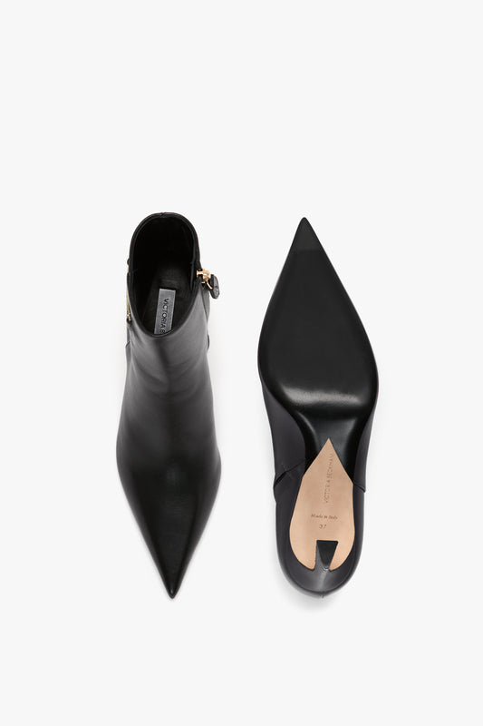 A pair of black Pointed Toe Half Boot In Black Soft Calf Leather, shown from top and sole views, with side zippers, a leather finish, and featuring a sculptural heel for an added touch of elegance by Victoria Beckham.