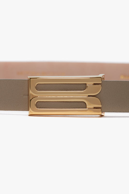 Close-up of a gold hardware belt buckle on a smooth calf leather belt, featuring a rectangular design. Exclusive Micro Frame Belt In Beige Leather by Victoria Beckham.