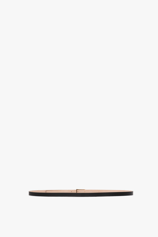 A minimalist image of an Exclusive Victoria Beckham Micro Frame Belt in Black Leather with small gold hardware, centered against a plain white background.