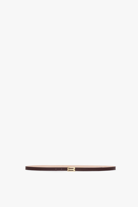 A thin brown Exclusive Micro Frame Belt In Burgundy Leather by Victoria Beckham made of smooth calf leather with a small gold buckle, displayed horizontally on a plain white background.
