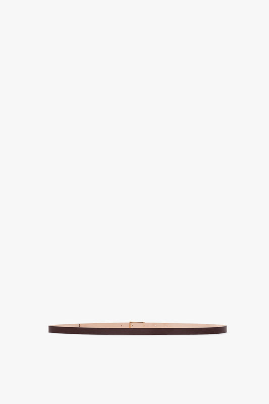 An Exclusive Micro Frame Belt In Burgundy Leather by Victoria Beckham, featuring gold hardware and a gold buckle, displayed on a white background.